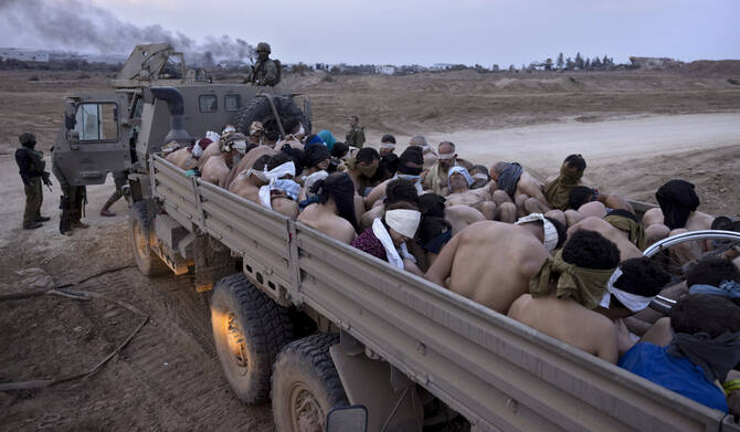 Israeli soldiers stand by a truck packed with bound and blindfolded Palestinian detainees, in Gaza, Dec. 8, 2023. (AP)